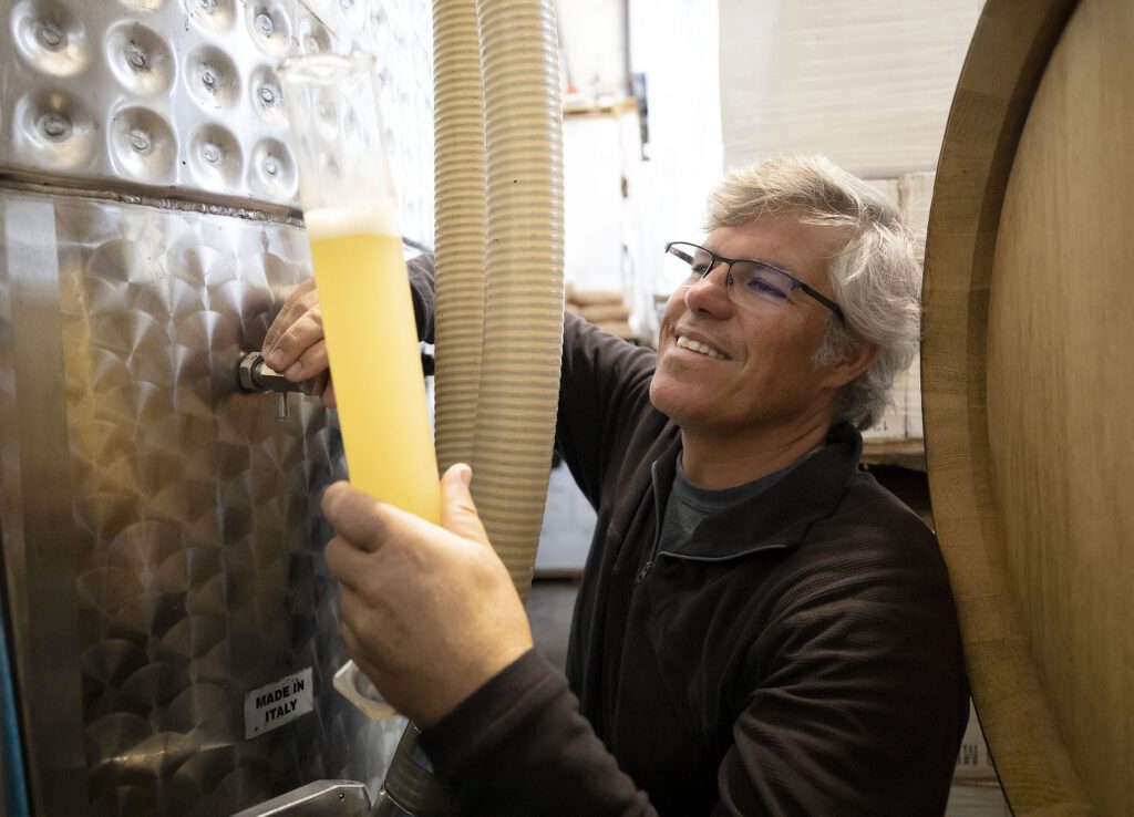 A man pours wine from a barrel at Chatham Vineyards