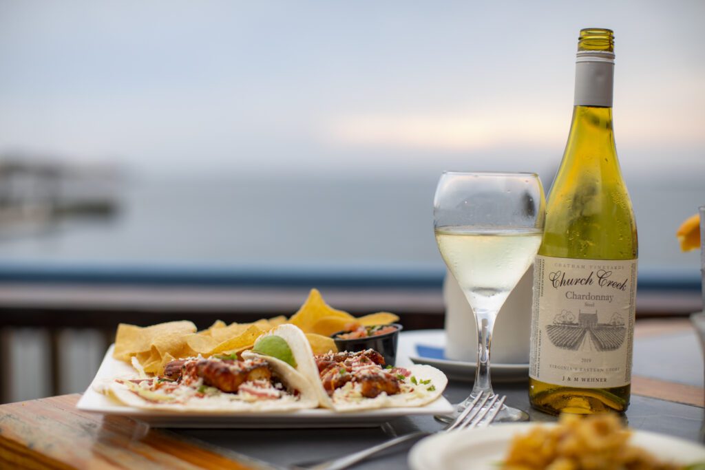 Chatham Chardonnay bottle on a table with a glass poured and seafood tacos on a plate