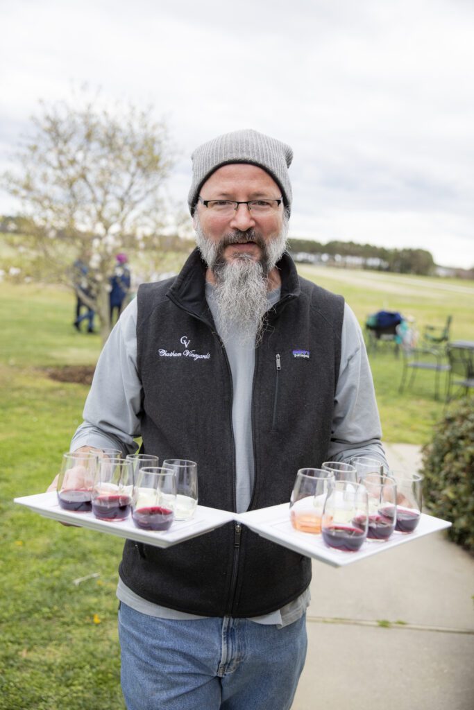 Ethan Watkins holding wine glasses filled with Chatham Vineyards wine