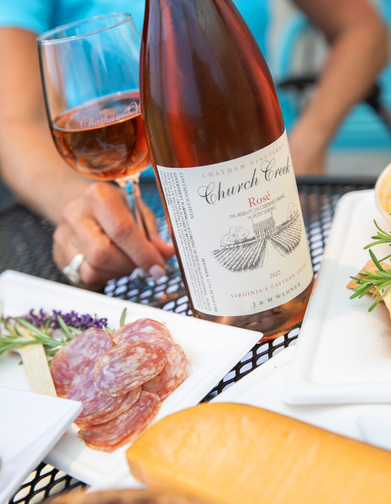 Bottle of Chatham Vineyards Rose on a table with charcuterie being enjoyed