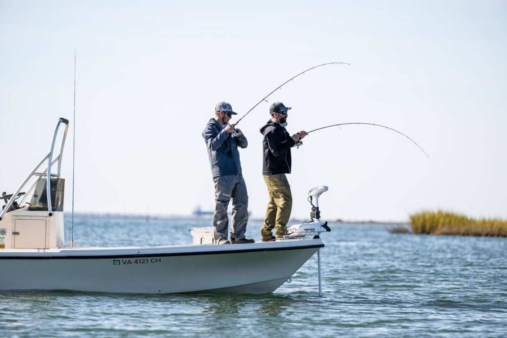 Two men fishing off the side of a boat